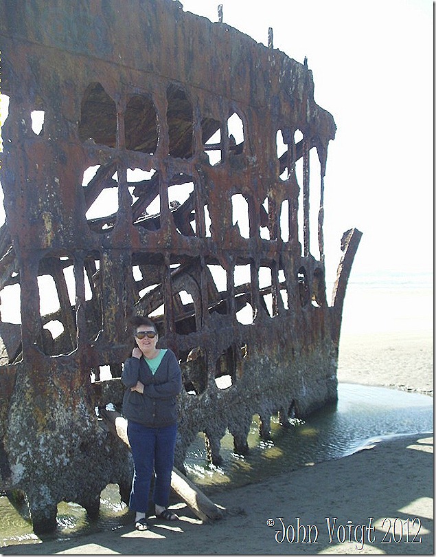 Here I am at the wreck of the Peter Iredale. That smile on my face looks more like a grimace of pain. Janalyn Voigt at wreck of Peter Iredale